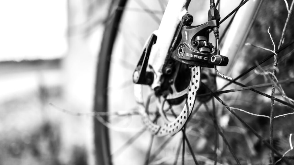 Detailed monochrome close-up of a bicycle disc brake on an outdoor ride. Proven Bike Maintenance Tips