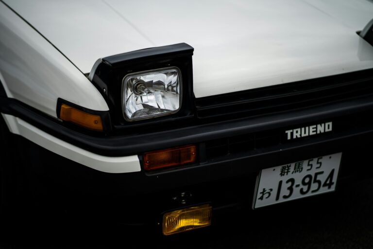 Close-up of a classic white Toyota AE86 Trueno with pop-up headlights.
