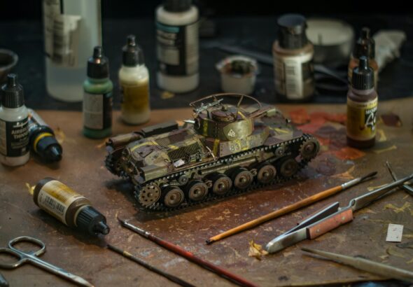 High-quality model tank surrounded by various painting supplies for a realistic diorama.